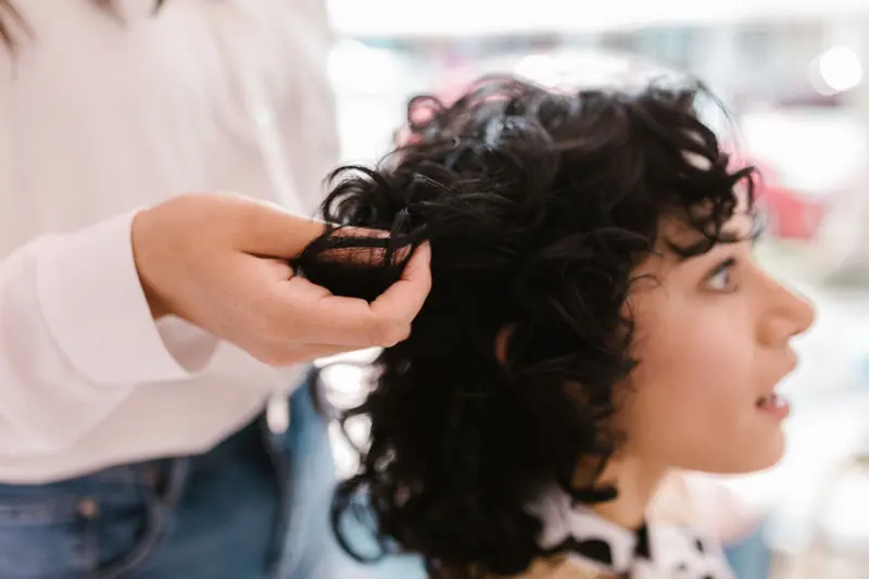 Close-up of a woman getting her hair styled indoors, showcasing self-care and salon expertise.