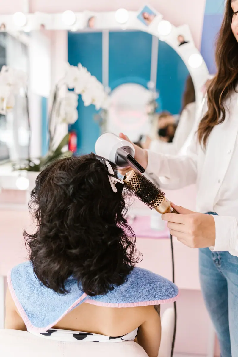 Stylist round-brushing a curly-haired client