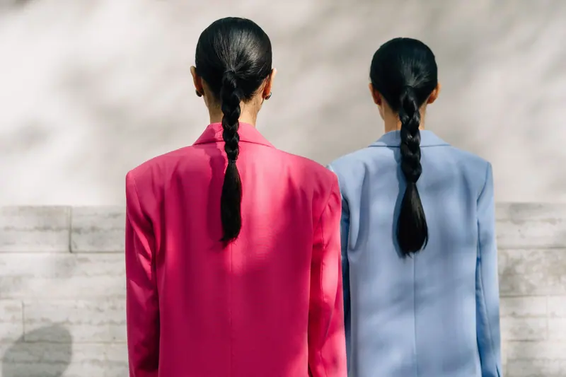 Stylish fashion photography featuring two models with ponytails in colorful blazer jackets.