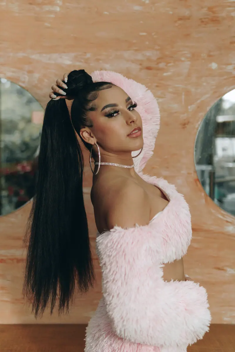 Portrait of a stylish woman with long black hair in a pink fur outfit in São Paulo.
