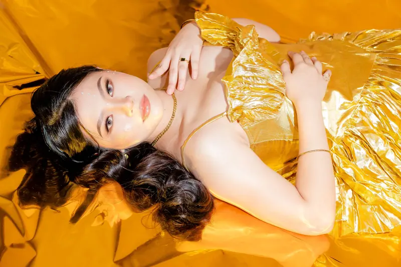 Woman with long dark waves lying on golden fabric