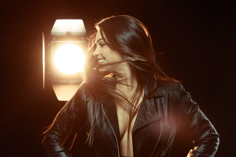 Dynamic photo of a woman in a black leather jacket against a dramatic studio backdrop.