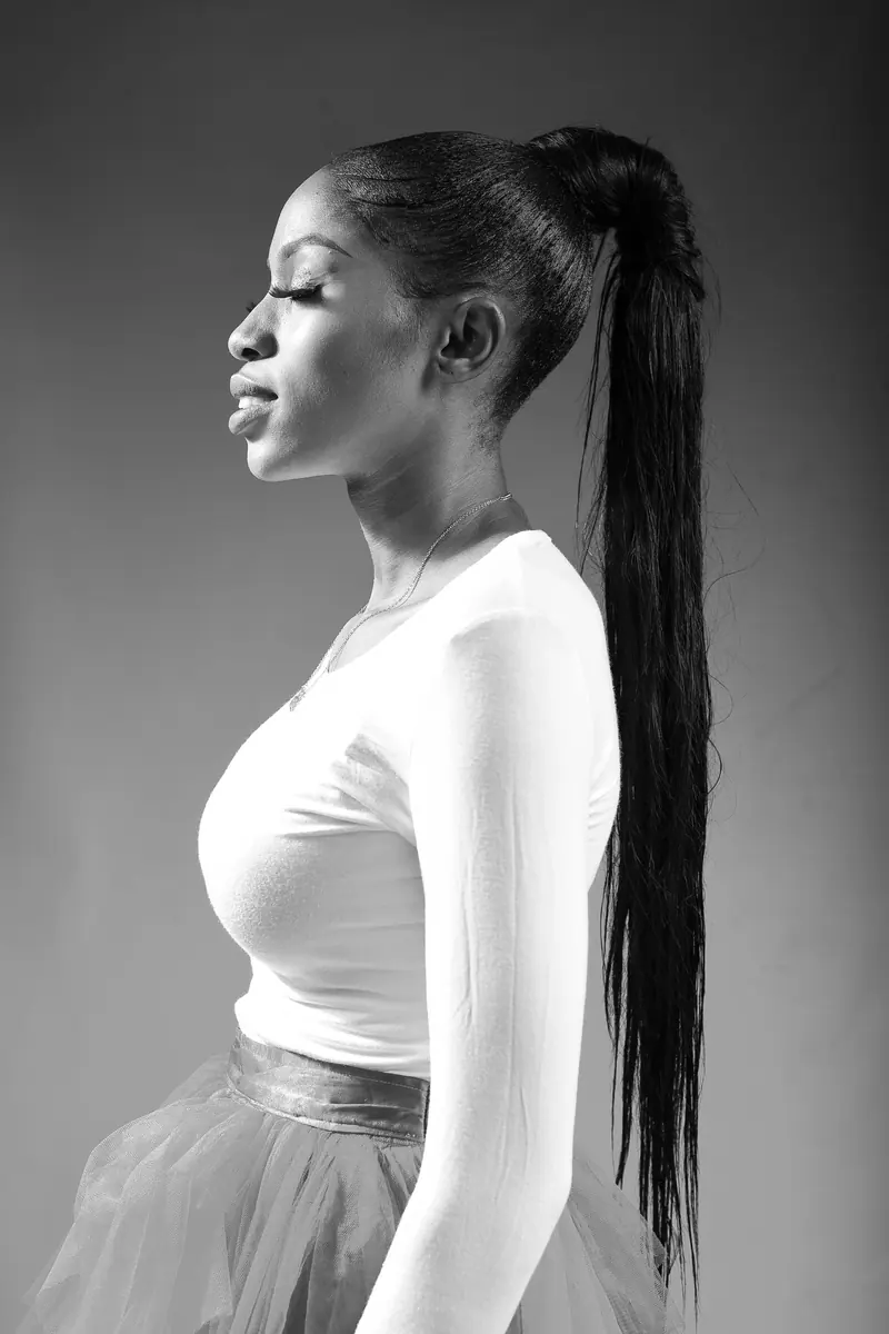 Black and white profile portrait of a poised ballerina in a studio setting, showcasing grace and elegance.