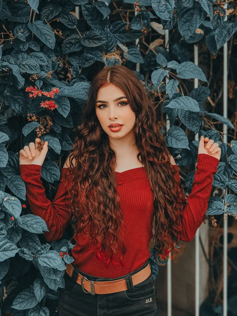 Long red curls against dark ivy