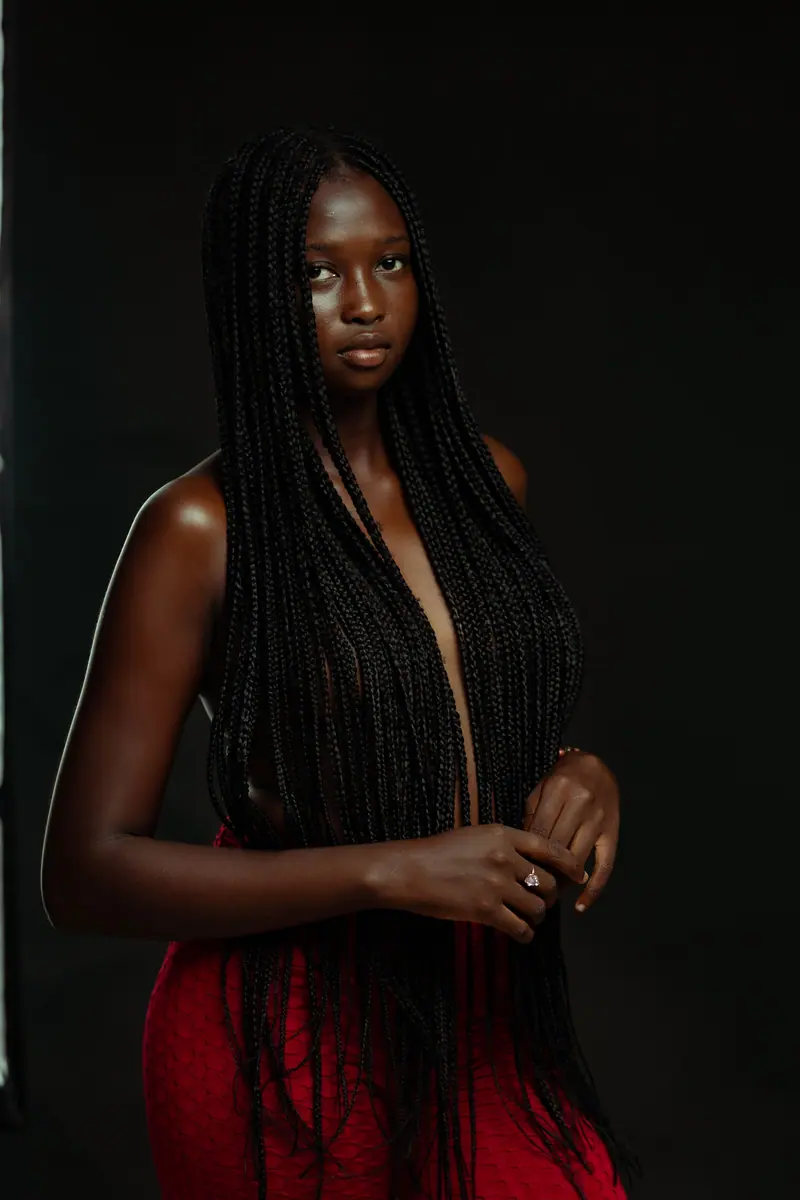 Captivating portrait of a woman with long braided hair against a dark background.
