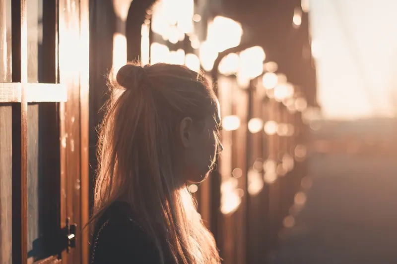Long hair silhouetted in golden window light