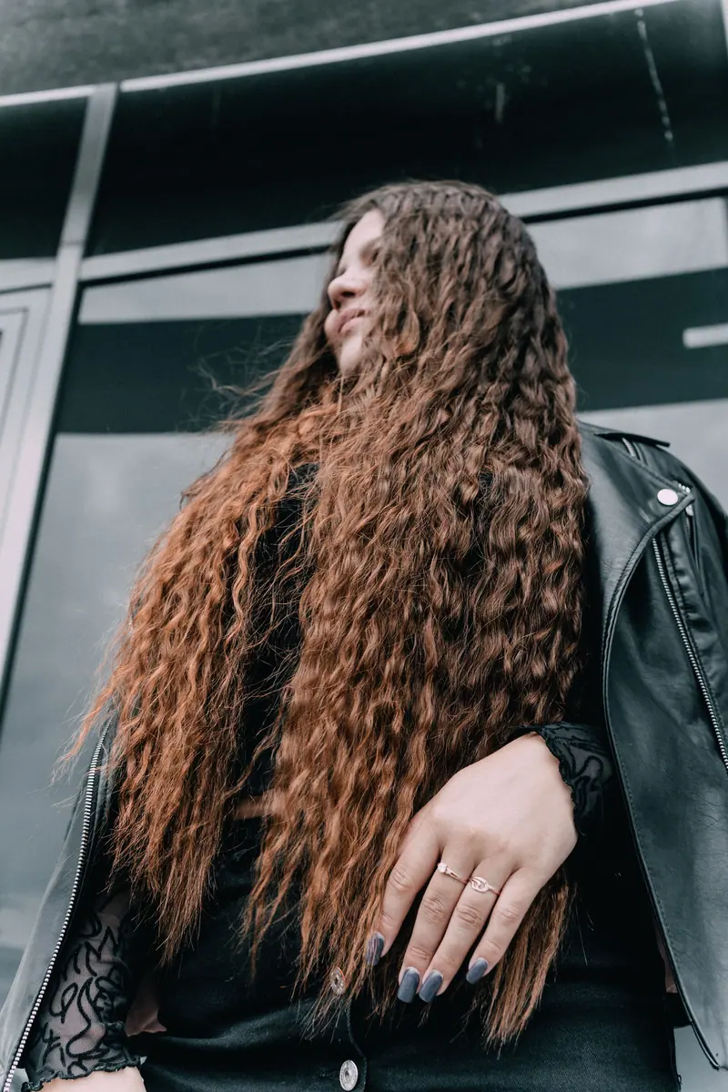 Stylish portrait of a woman with long curly hair and leather jacket, outdoors in Emden, Germany.