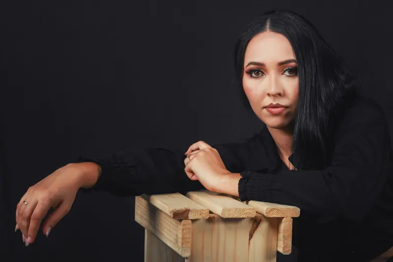 Sophisticated portrait of a woman with long black hair posing against a dark backdrop.