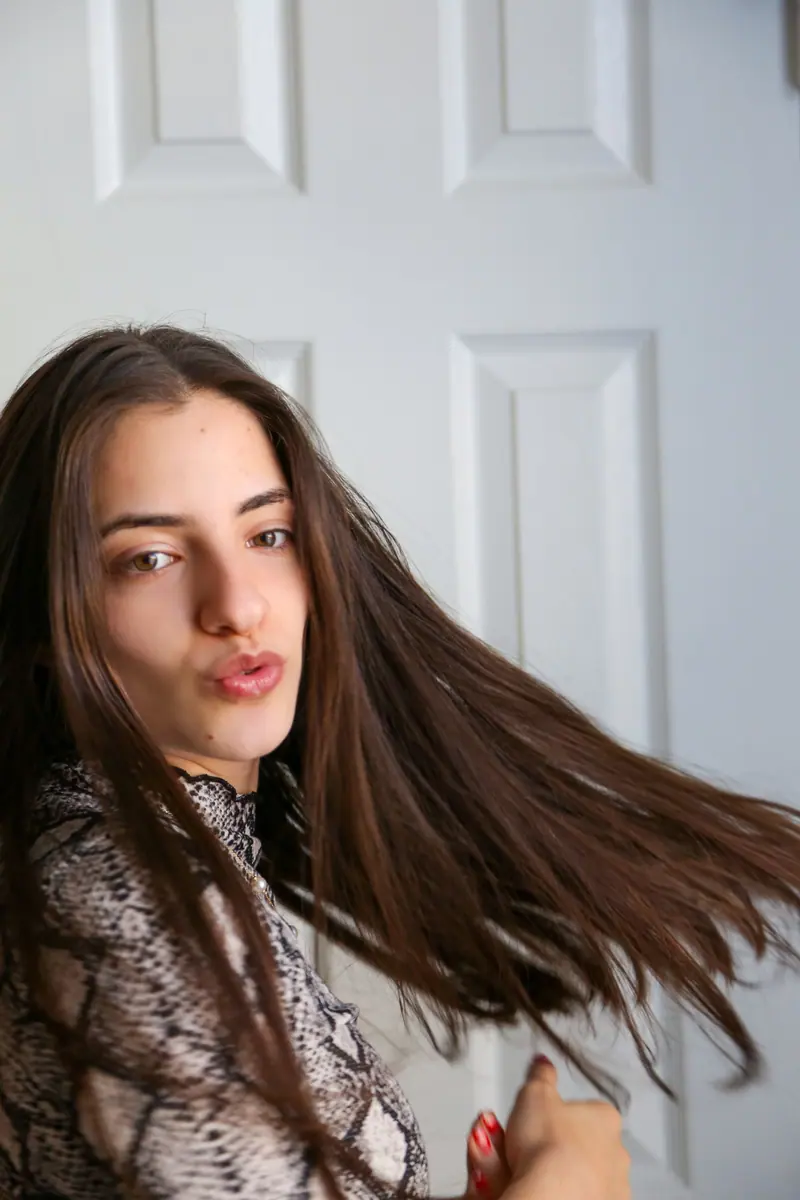 Long brunette hair in motion against a white door