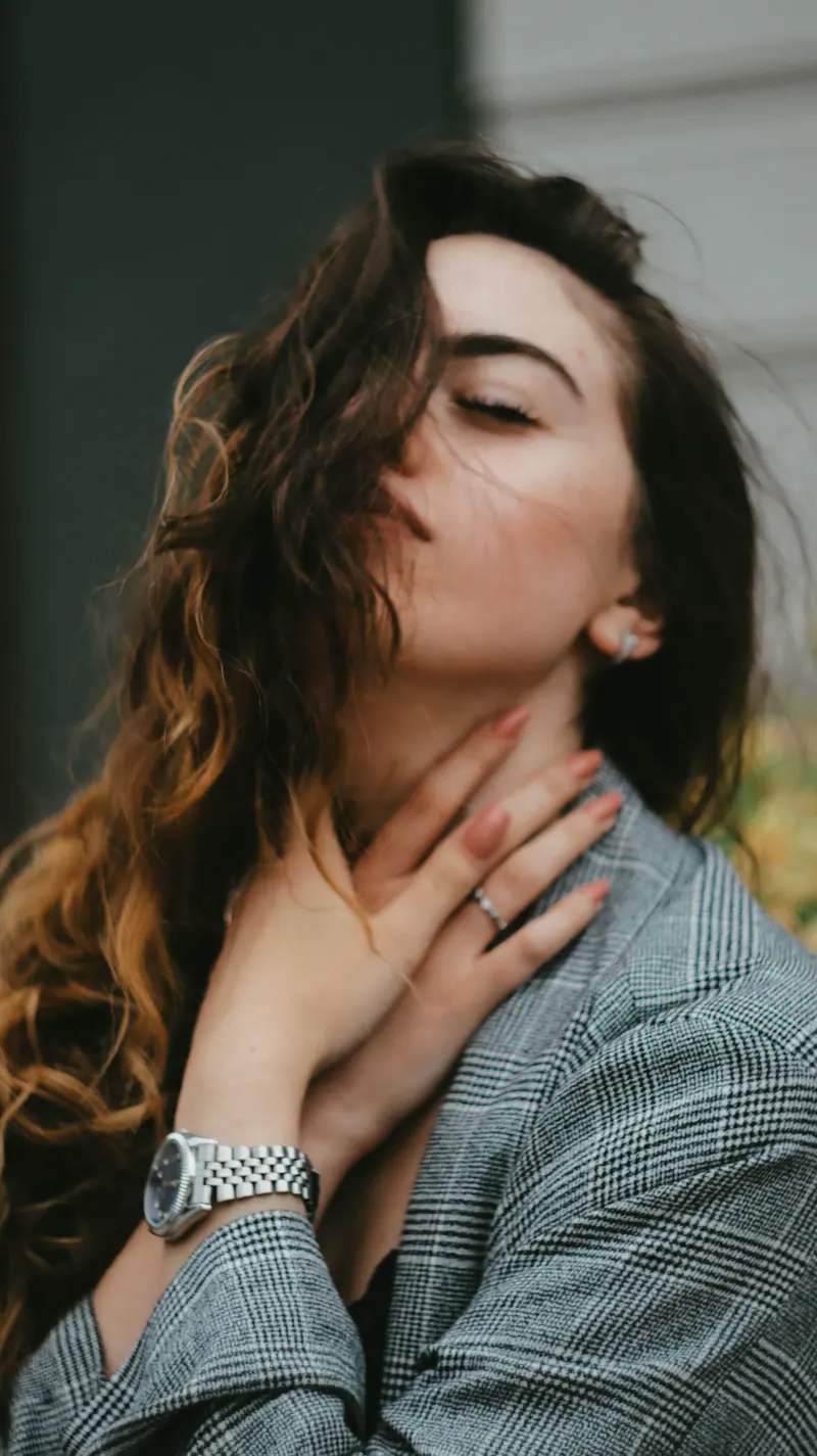 A serene outdoor portrait of a woman with wavy hair and eyes closed, exuding tranquility.