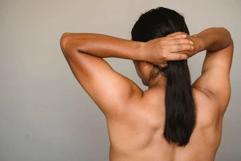 Faceless anonymous portrait with arms raised, posing in a studio setting.