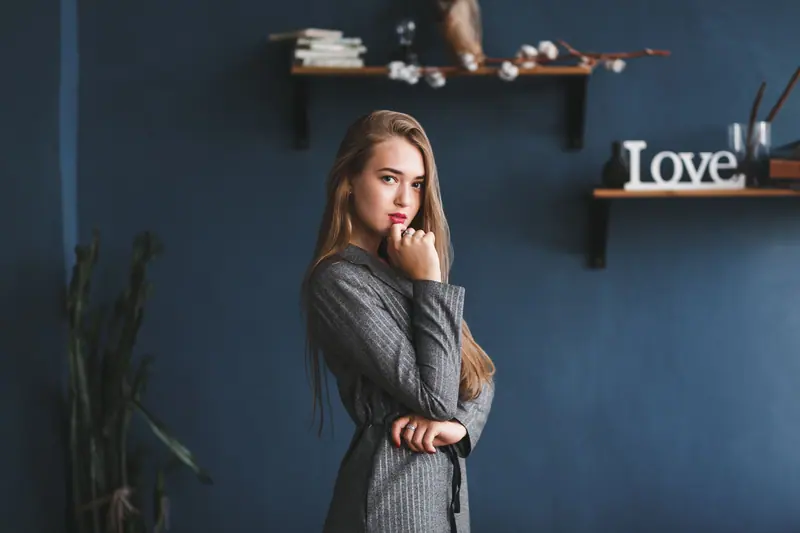 Woman with long blonde hair in a grey suit against a navy wall