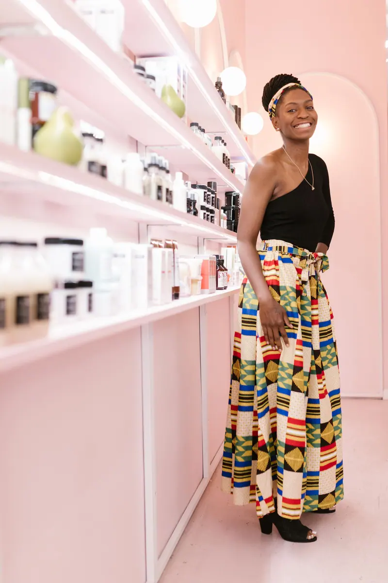 Fashionable woman posing gracefully in a vibrant salon interior with a smile.