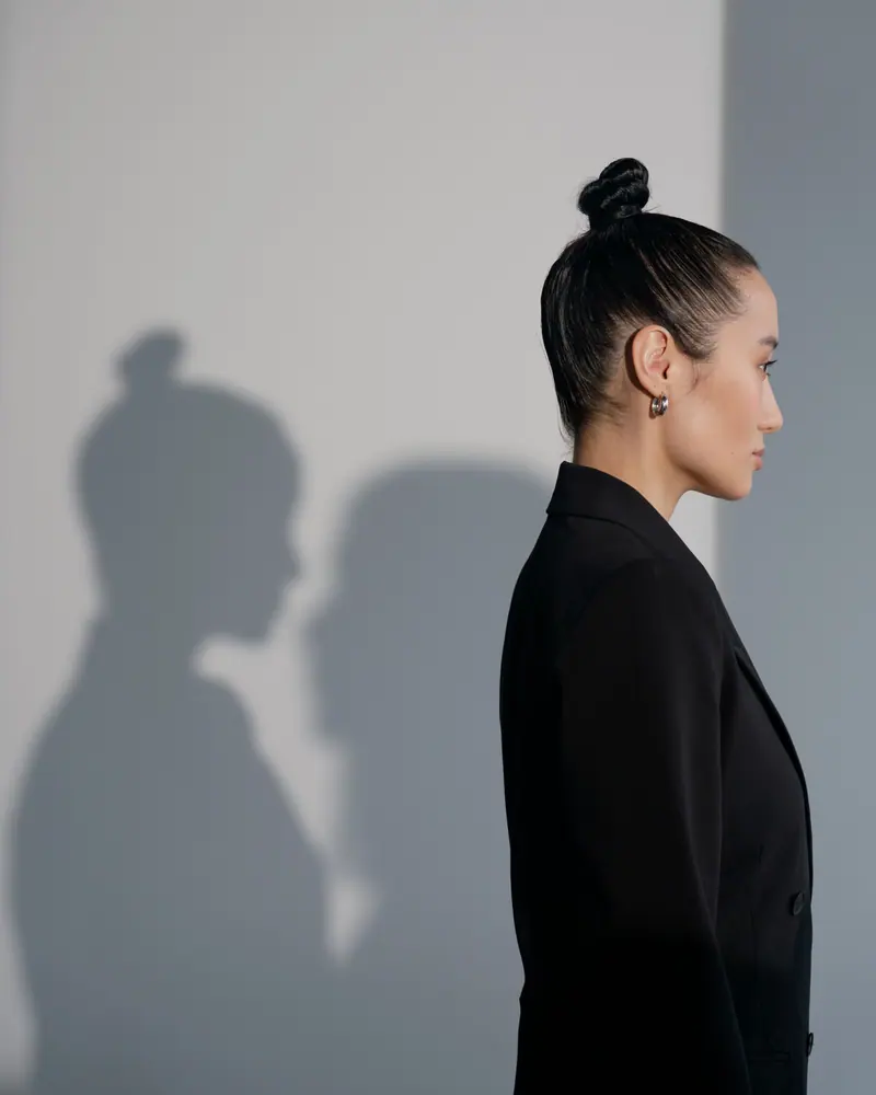 Profile of a woman with a sleek top knot against a pale wall