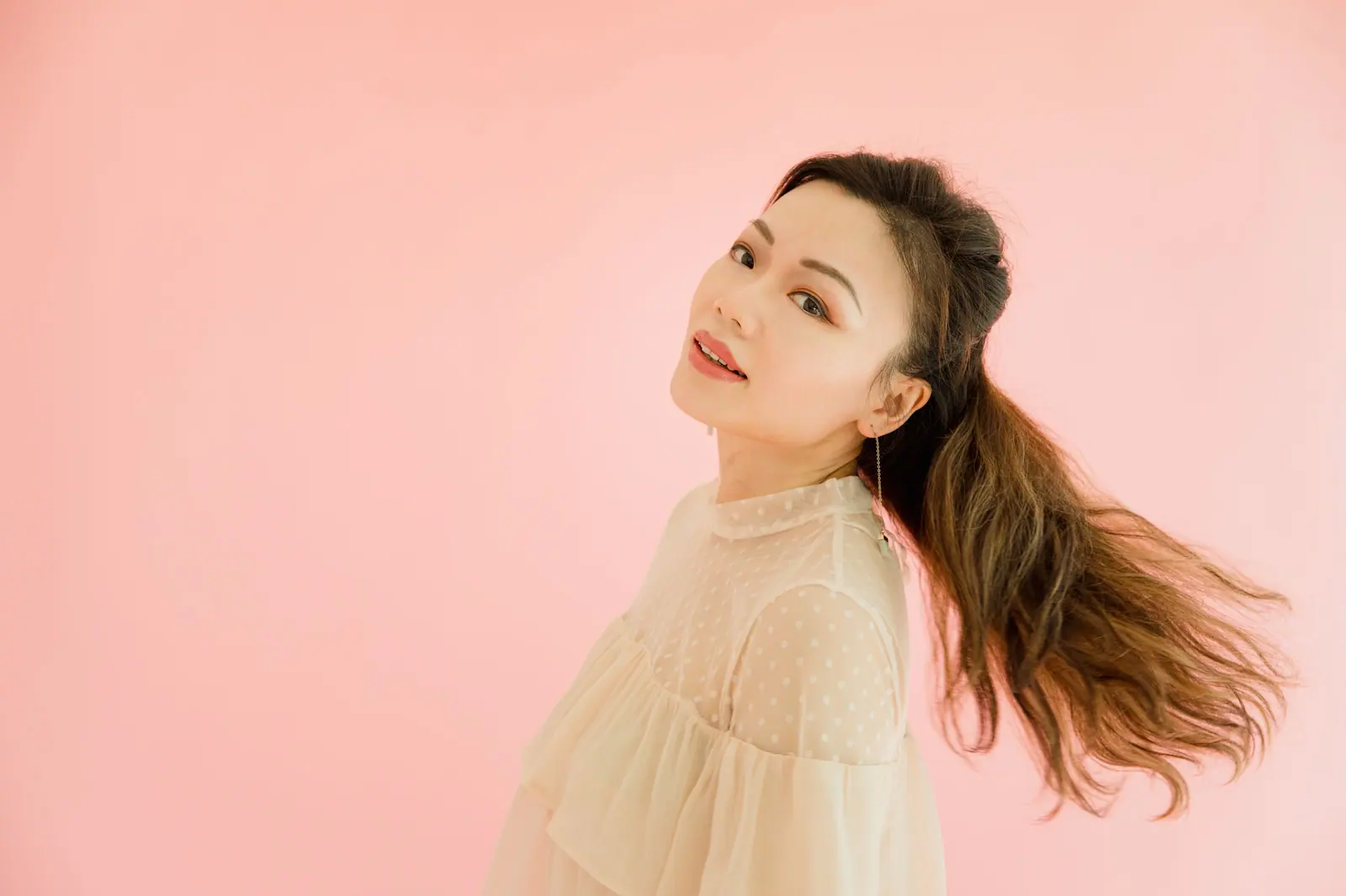 Long hair swinging against a blush wall