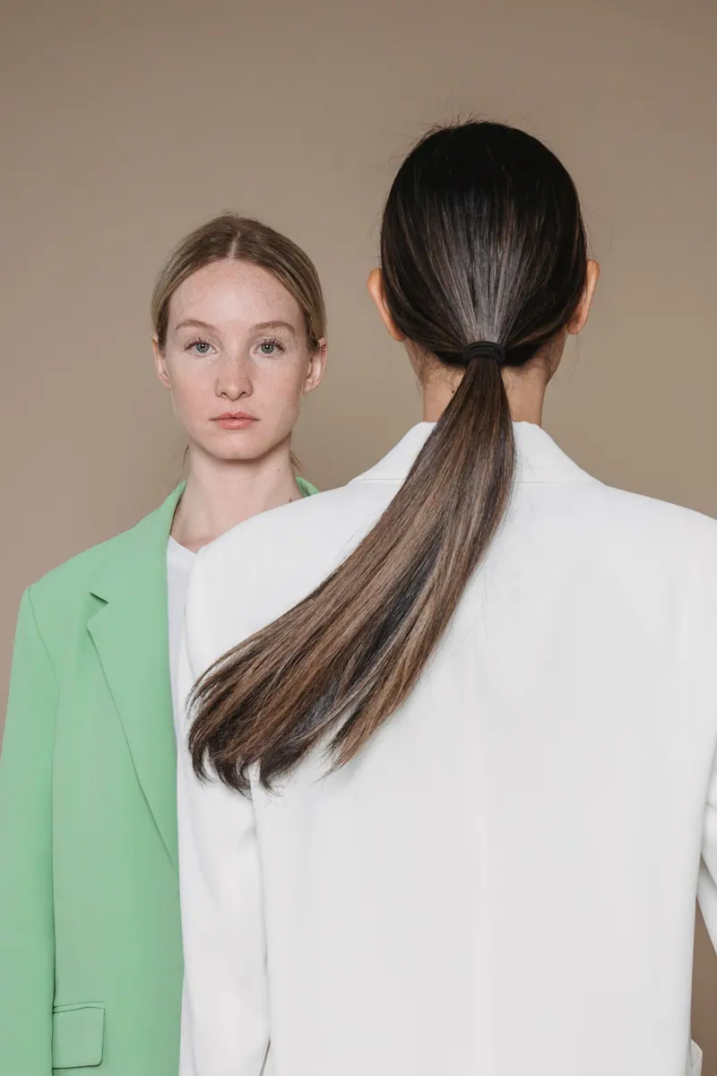 Two women, one with a low, glossy ponytail