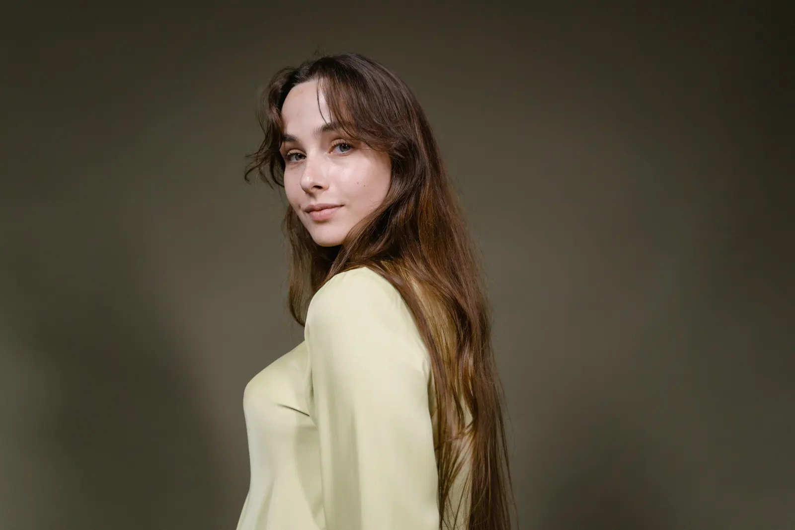 Long glossy brown hair against an olive backdrop