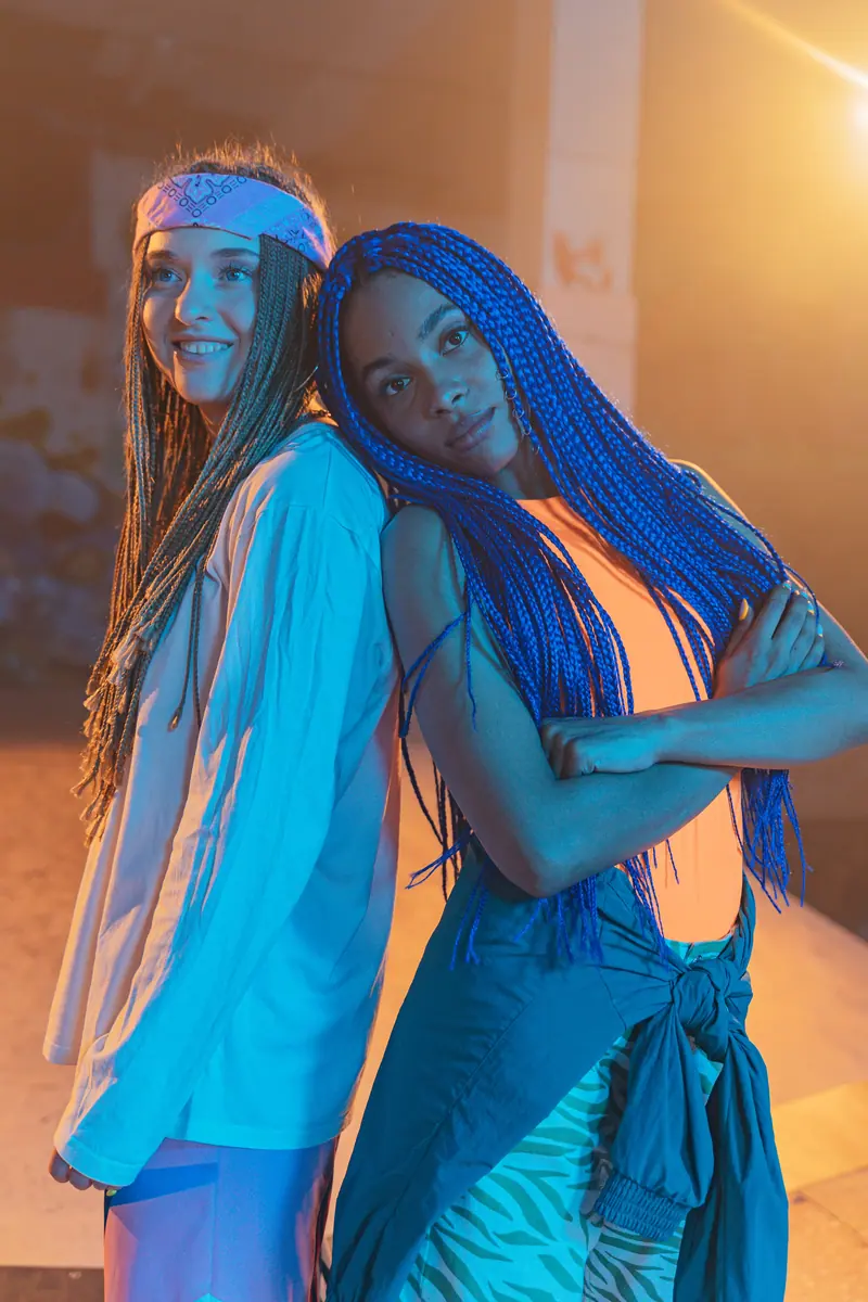 Stylish women with colorful box braids posing confidently indoors.