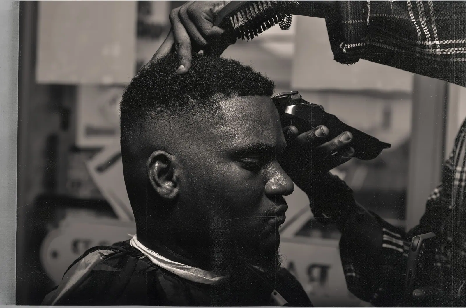 Barber edging a crisp fade on a client, in black and white