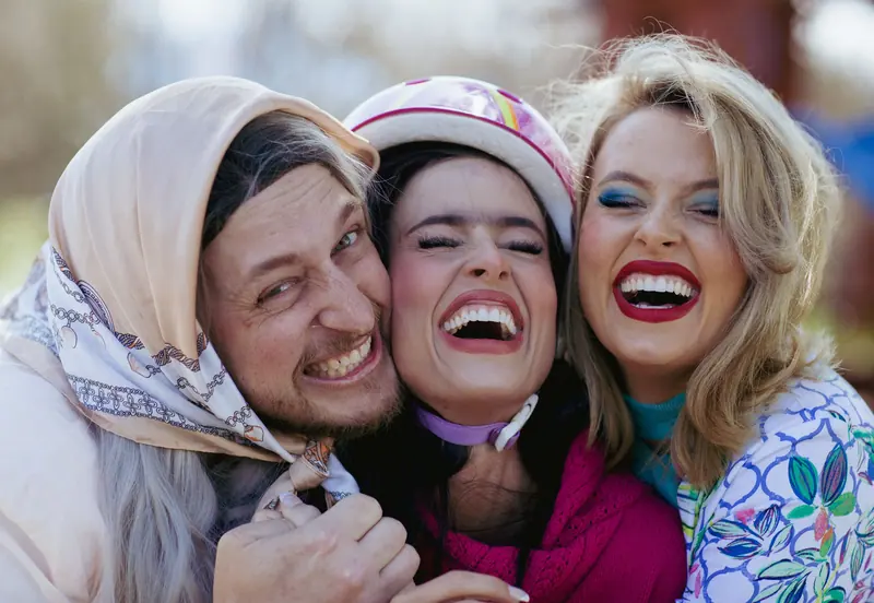 Three friends laughing joyfully outdoors, capturing happy moments together.