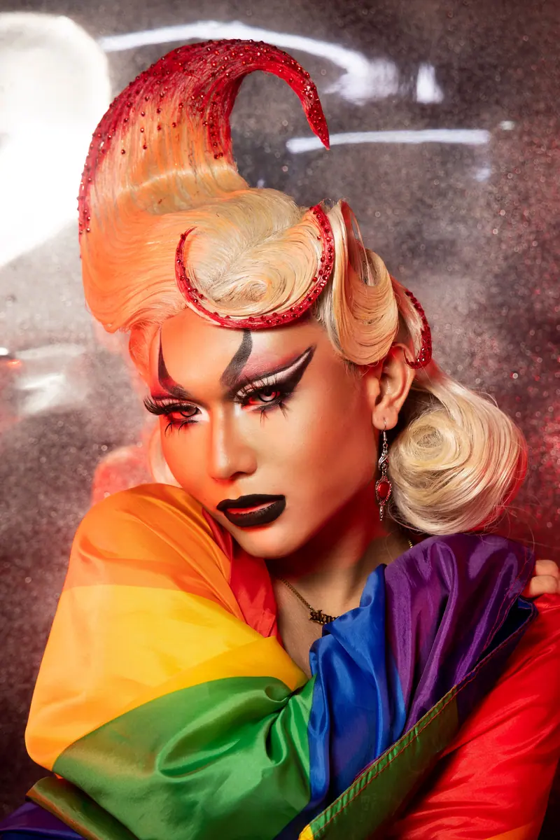 Drag look with a sculpted copper wig and a rainbow scarf
