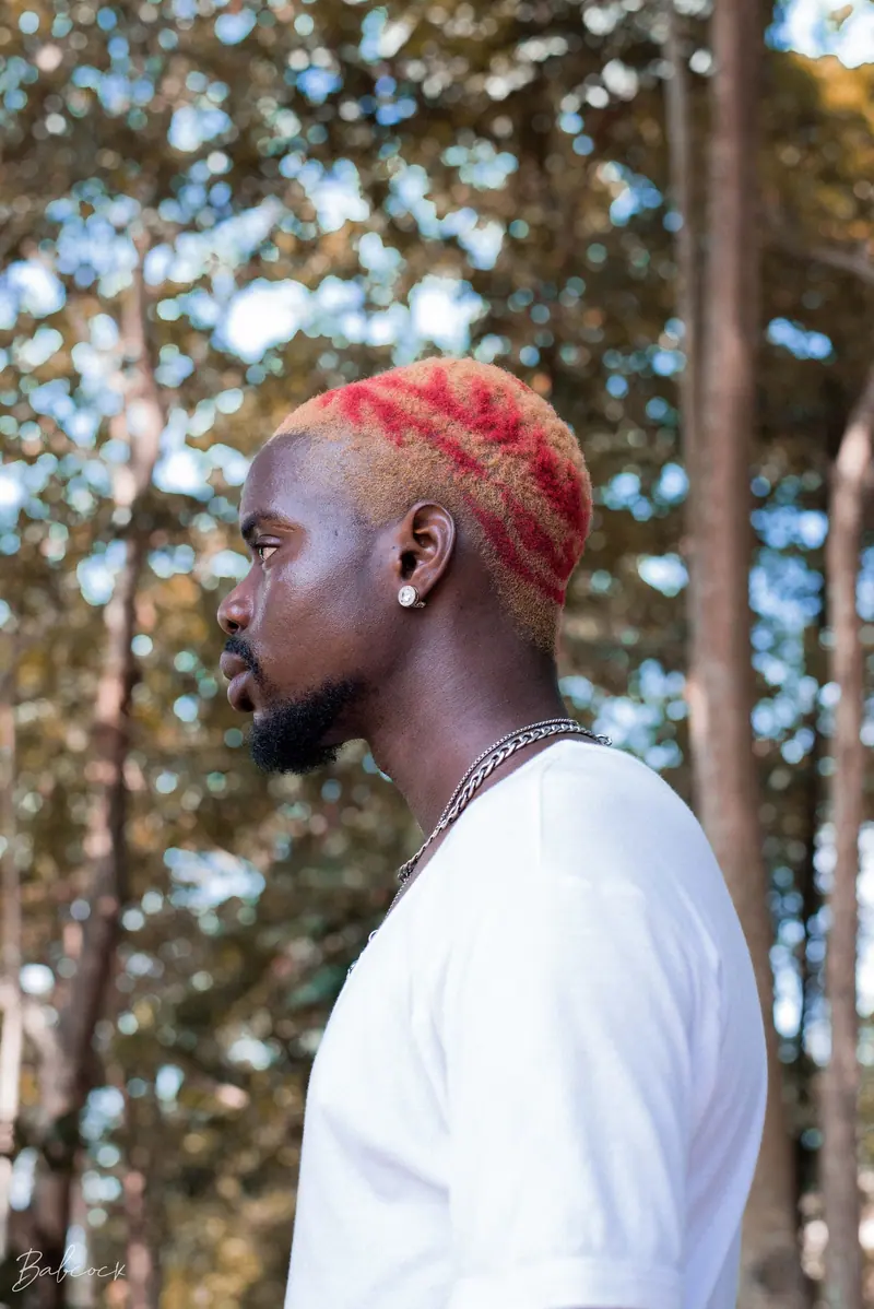Man with a bright red patterned buzz cut in profile