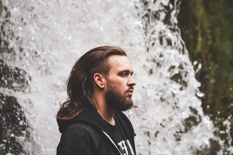 Long hair tied back beside a waterfall