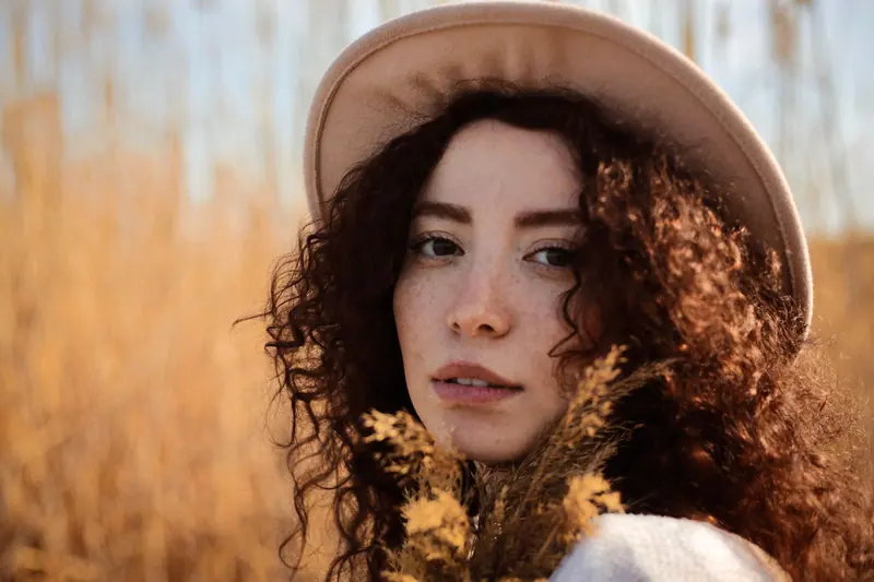 Curls and a felt hat in golden light