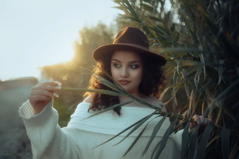 Curls under a felt hat at golden hour