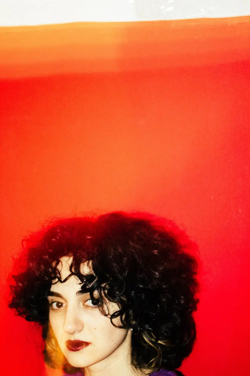 Black curls with a soft fringe against a red wall