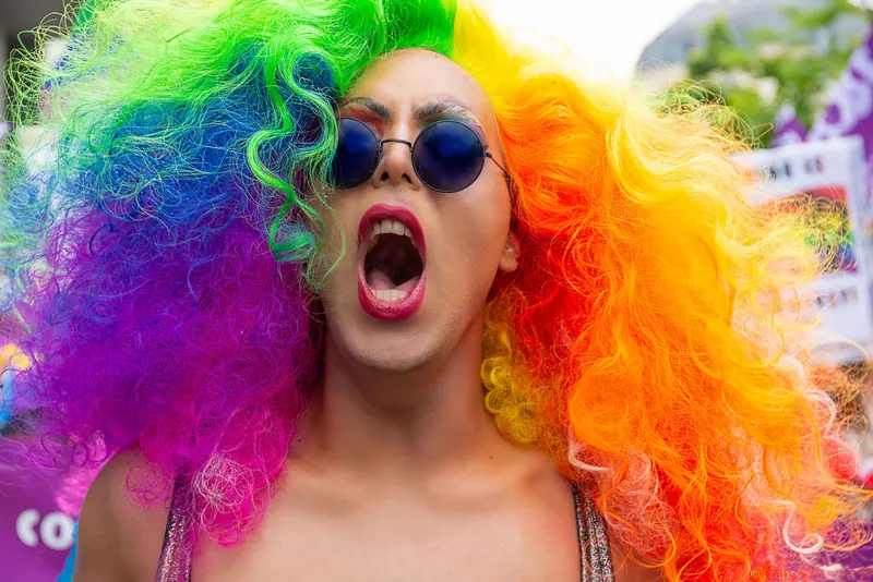 Joyful crowd member in a huge rainbow wig