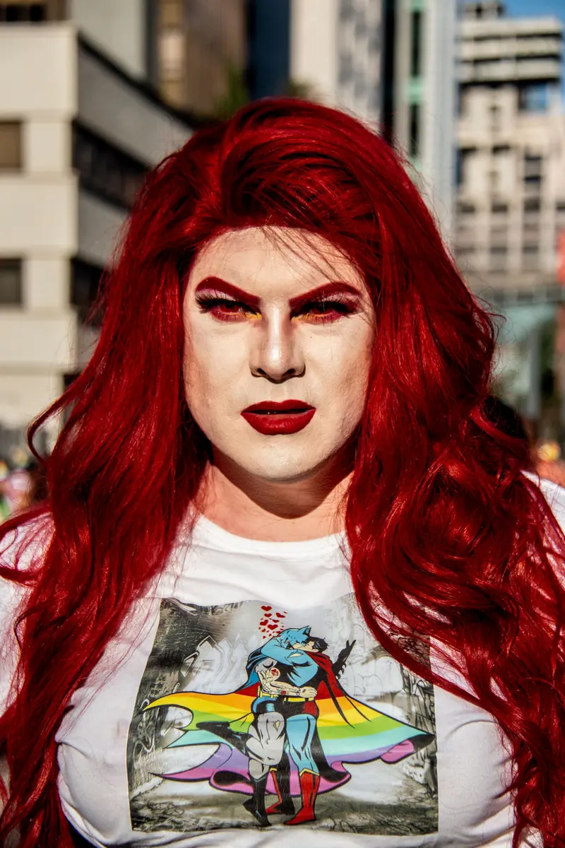 Drag performer with long red curls and a rainbow tee