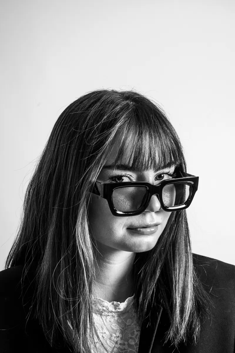 Stylish black and white portrait of a woman wearing oversized glasses, exuding confidence.