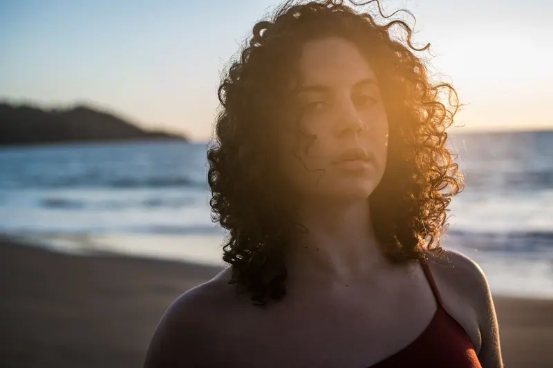 Dark curls at sunset by the water