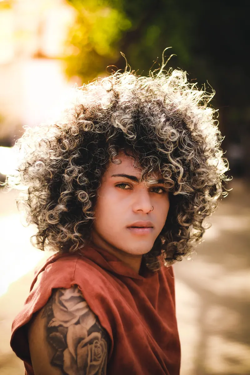 Portrait of a person with big highlighted curls in warm afternoon light