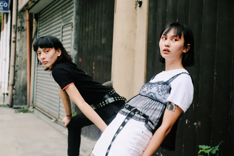 Two fashionable individuals posing confidently in an urban street setting.