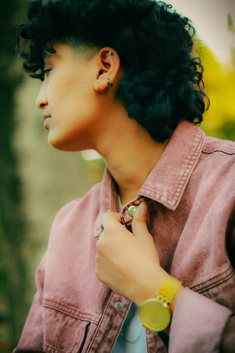 Short dark curls and a dusty-pink jacket