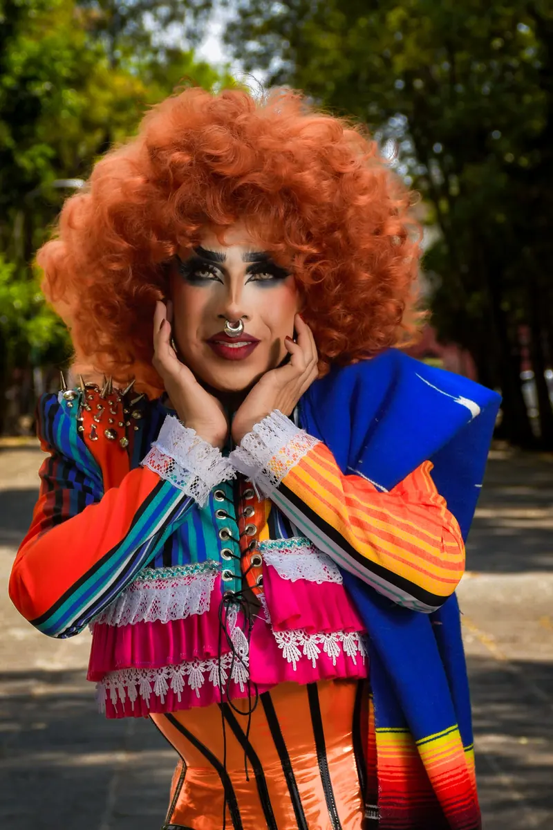 Performer with a copper afro wig in a striped, rainbow outfit
