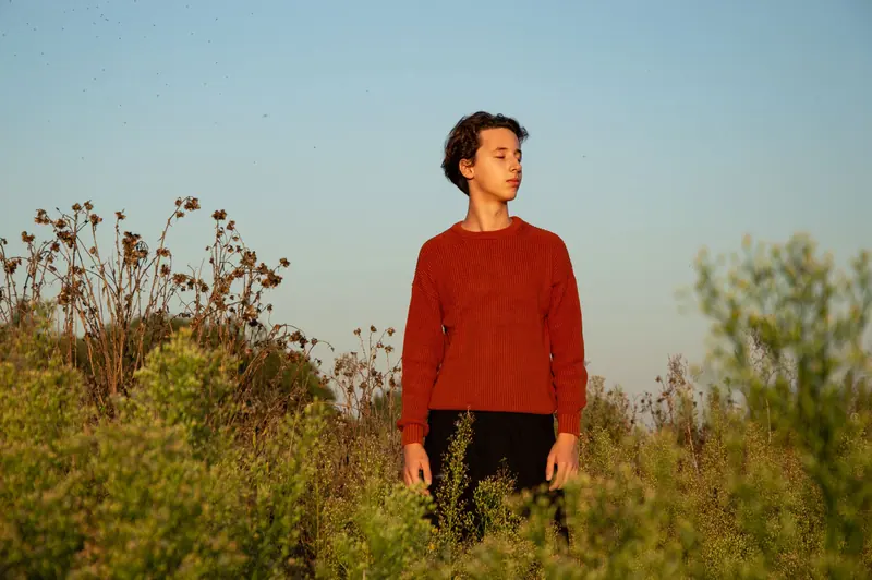 Short dark curls in a sunlit wildflower field