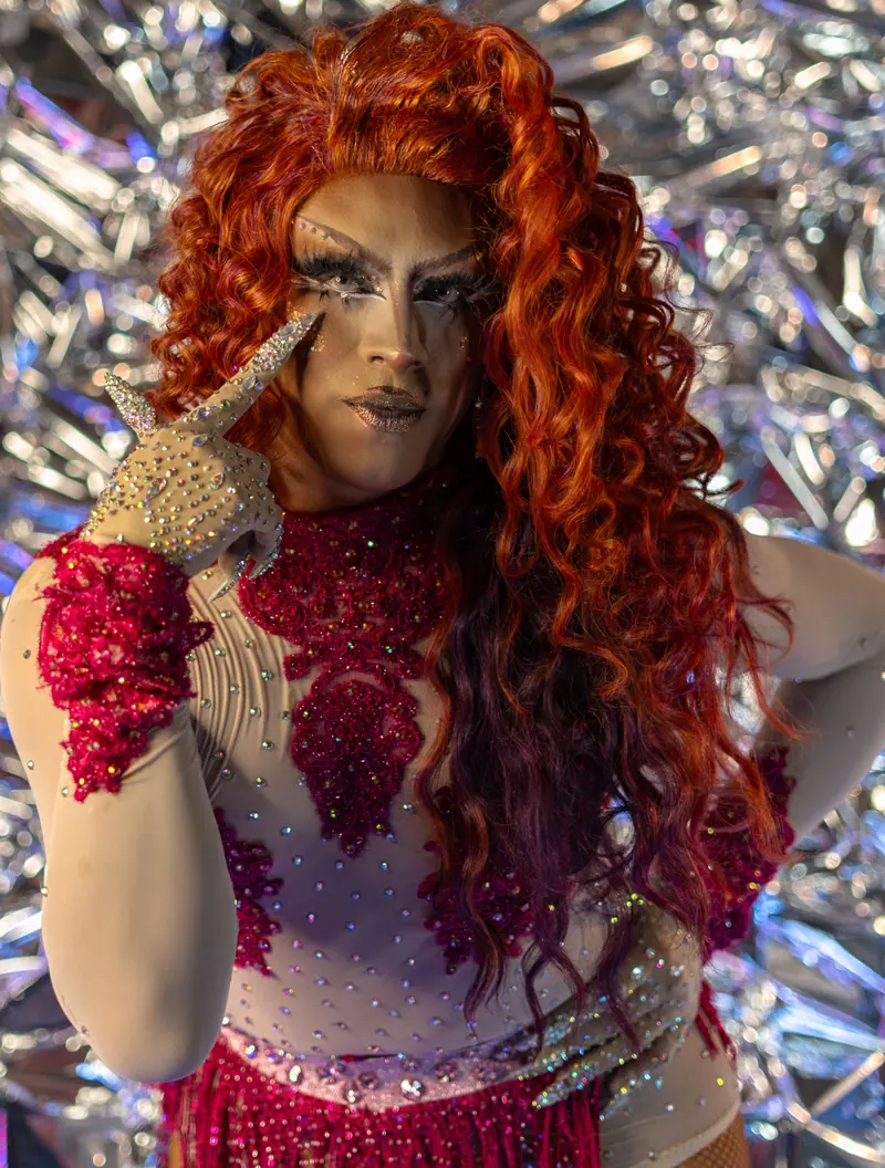 Performer with long red curls against shimmering foil