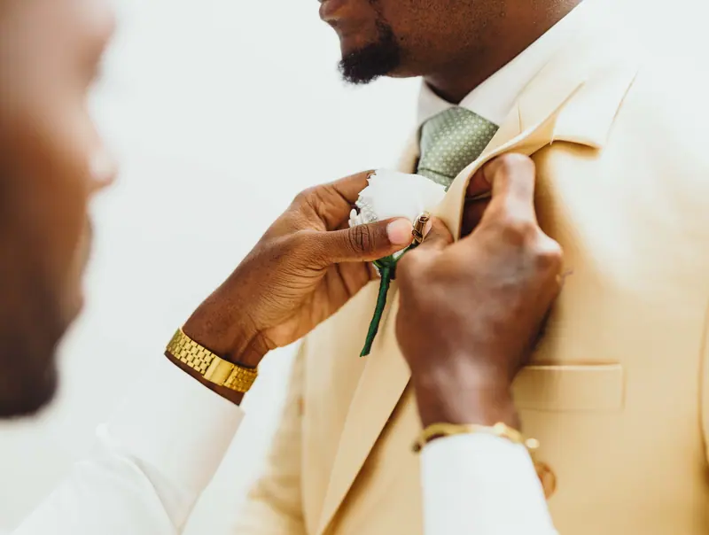 Pinning a boutonniere on a cream suit