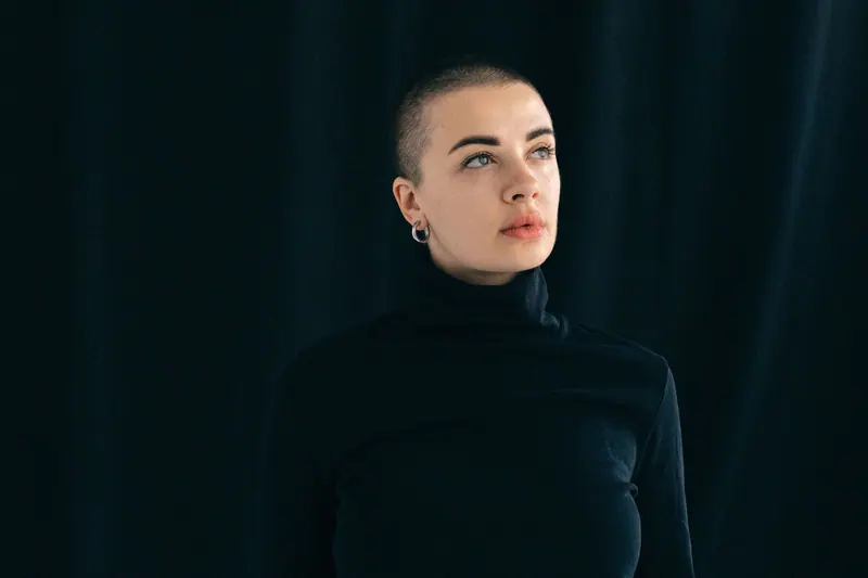 Stylish portrait of a woman in black, looking thoughtfully upward.
