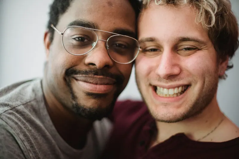 Couple smiling, one with glasses and a fade
