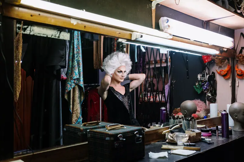 Performer adjusting a wig at the dressing-room mirror