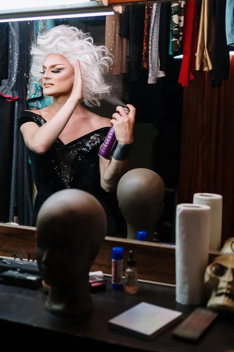 Wig heads and hairspray on the dressing-room counter