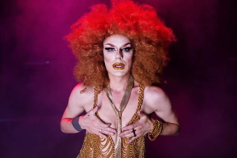 Drag look with a copper afro wig and gold chains