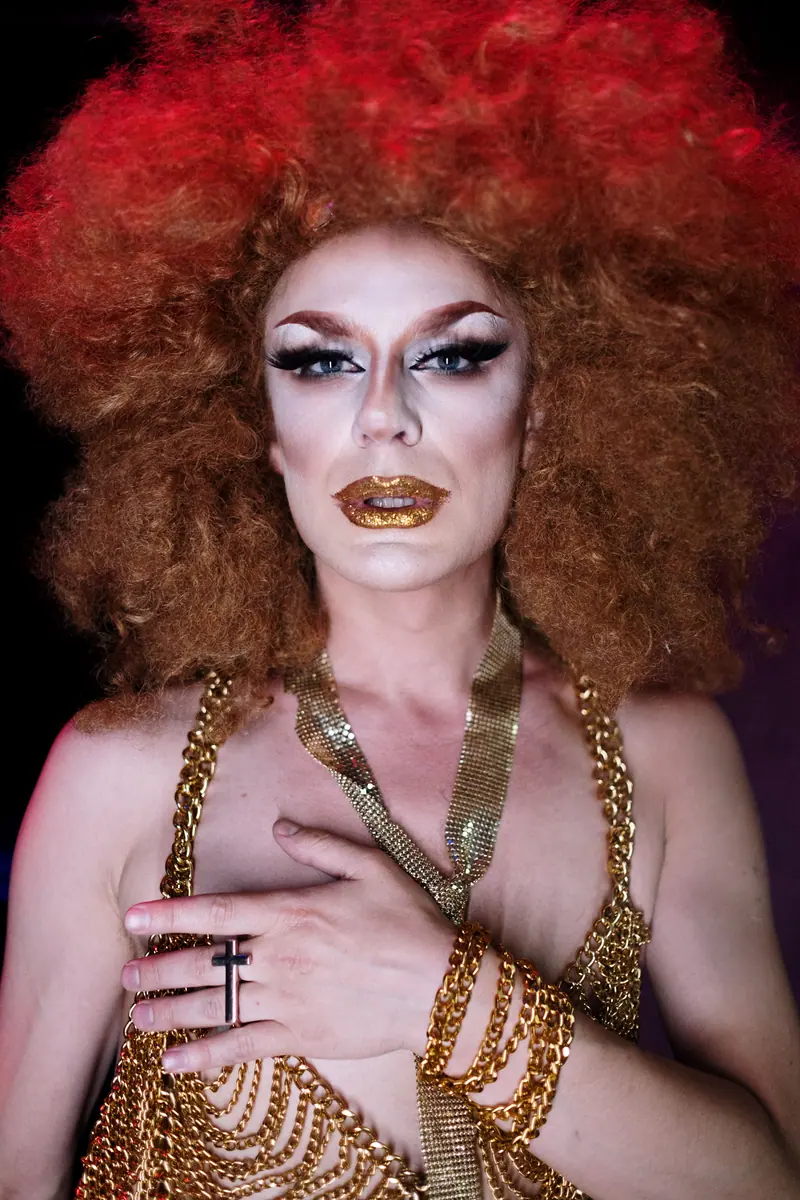 Performer with a voluminous copper wig and gold chains