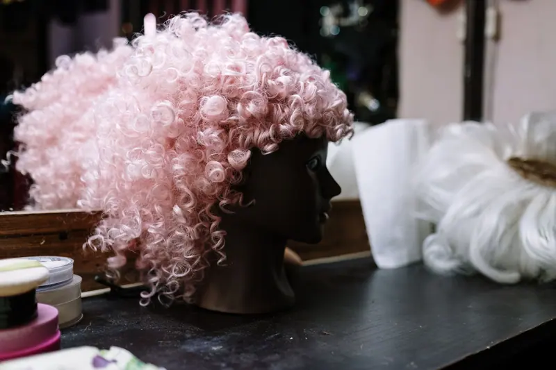 Pink curly wig resting on a wig head