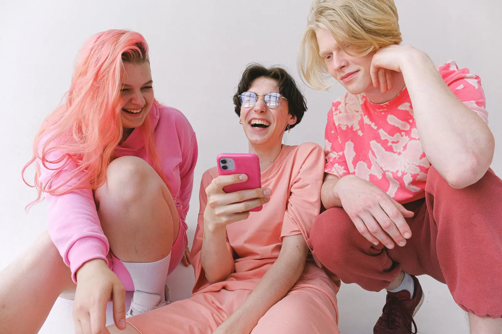 Three friends in pink laughing together, with pink and bleached hair