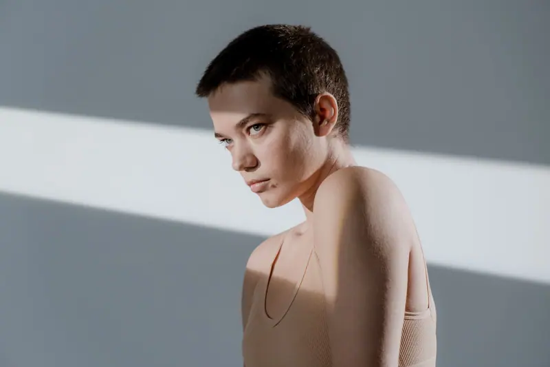 Close-up studio portrait of a woman with short hair in soft lighting, displaying a serious expression.